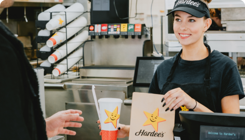 Hardees employee at the counter handing out the order to a customer